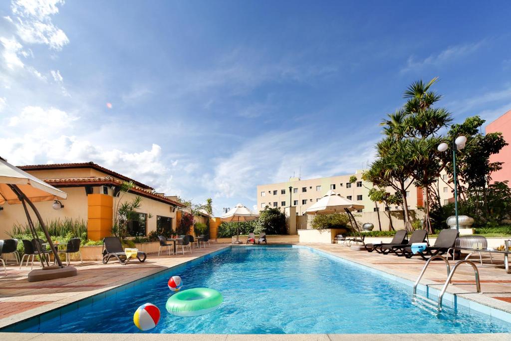 ein Pool mit Volleyball und Stühlen sowie ein Gebäude in der Unterkunft Sorocaba Park Hotel by Atlantica in Sorocaba