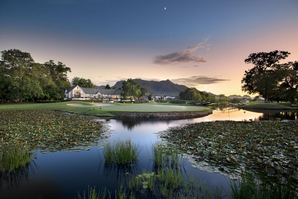 a lake filled with lots of green grass next to a body of water at Fancourt Hotel in George