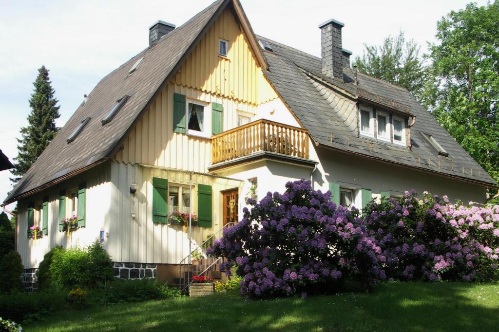 a large house with a balcony and purple flowers at Landhaus Wölfel in Bad Steben