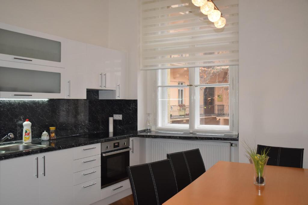 プラハにあるTiva Downtown Apartmentsの白いキャビネットと木製テーブル付きのキッチン