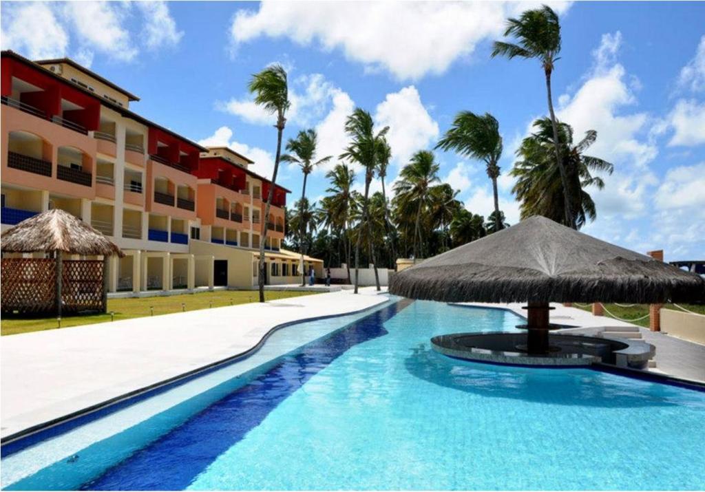 a swimming pool with an umbrella and a building at Costa Brava Praia Hotel in Lucena