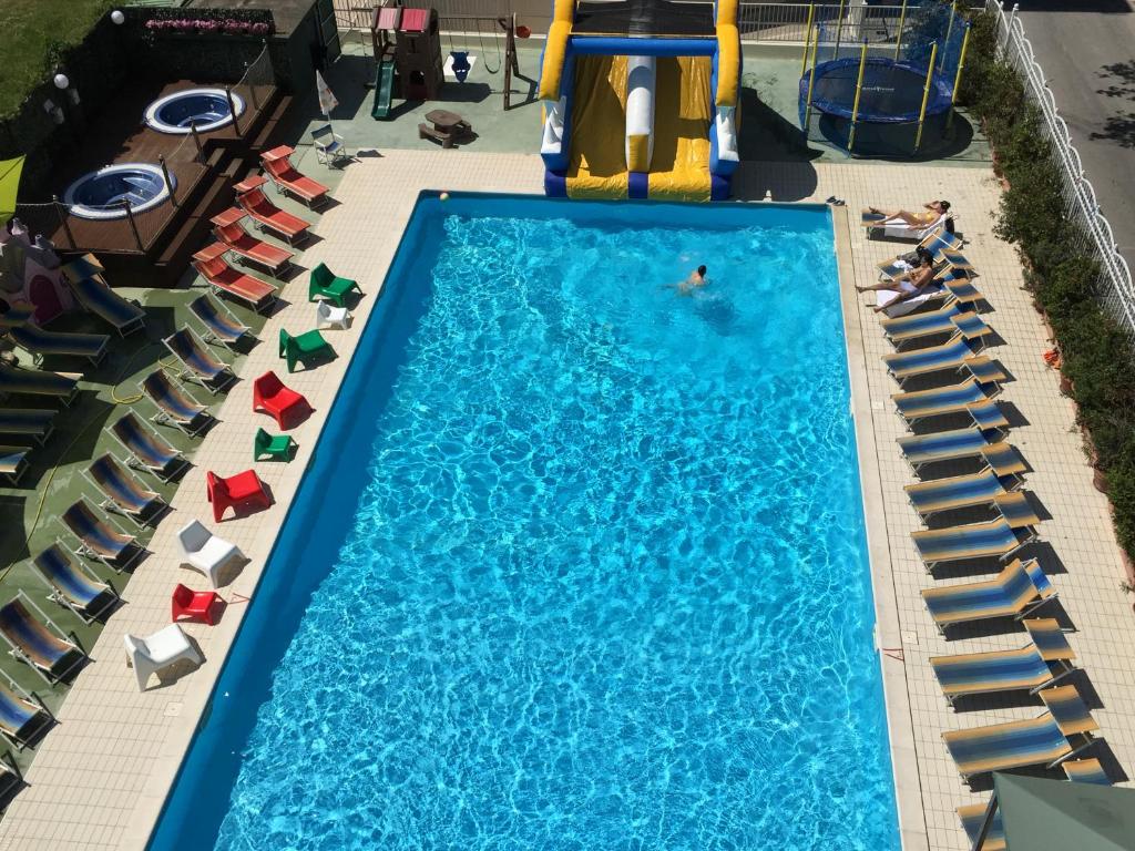 einen Blick über den Swimmingpool mit Stühlen in der Unterkunft Hotel Jumbo in Rimini