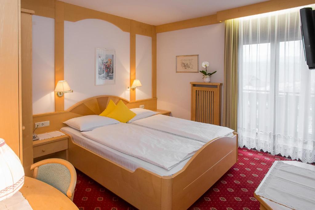 a hotel room with a bed and a window at Hotel Alexandres in Appiano sulla Strada del Vino