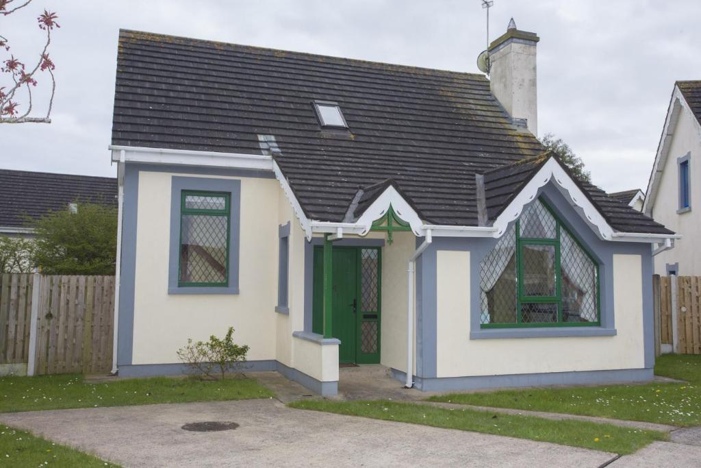een klein wit huis met een groene deur bij Willow Grove Holiday Homes No. 4 in Rosslare