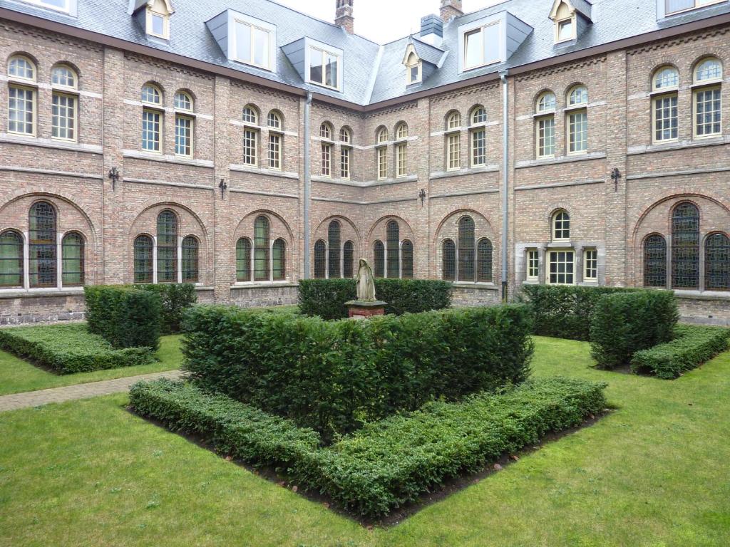 um grande edifício de tijolos com arbustos à frente em Albertushof em Ypres
