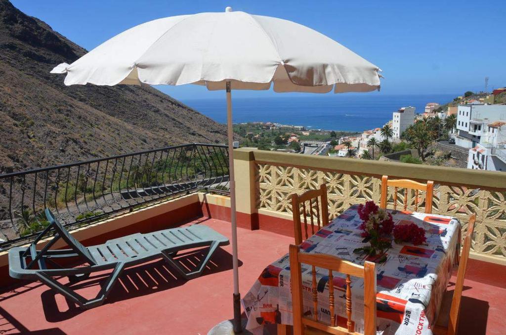 stół i krzesła pod parasolem na balkonie w obiekcie Apartamentos Gran Rey w mieście Valle Gran Rey