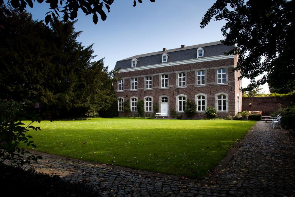 un gran edificio de ladrillo con un césped verde delante de él en B&B Het Agnetenklooster, en Maaseik