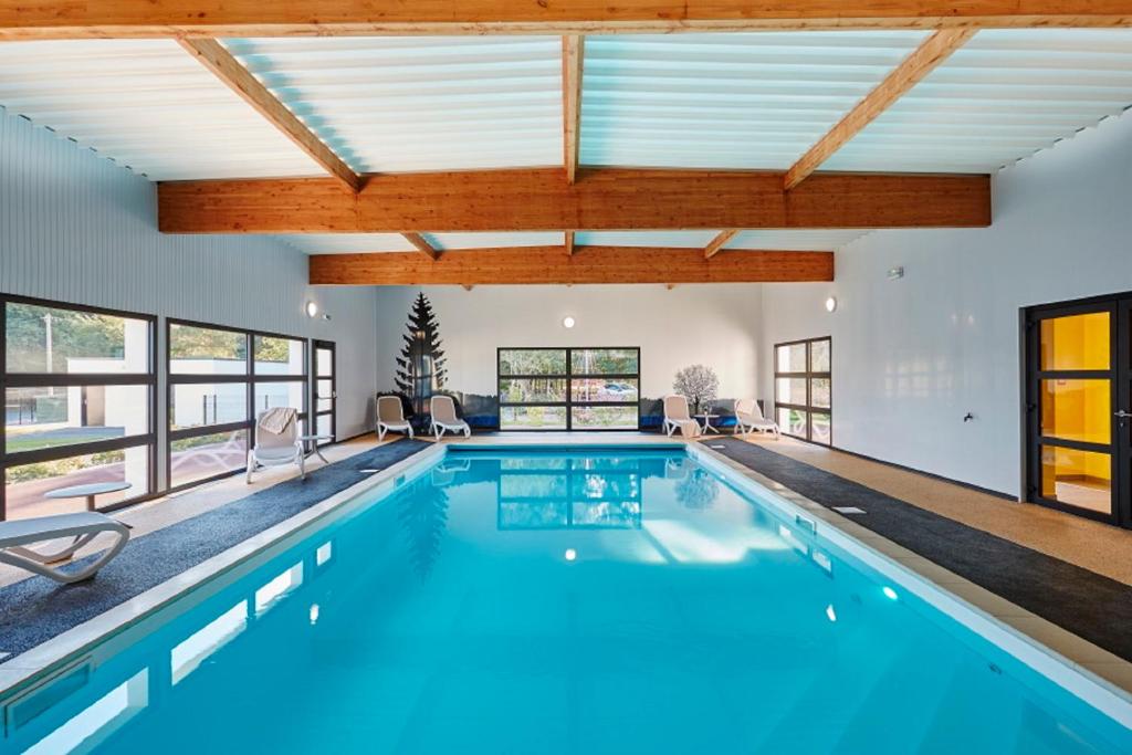 een binnenzwembad met blauw water in een huis bij Village by logis in Le Gâvre