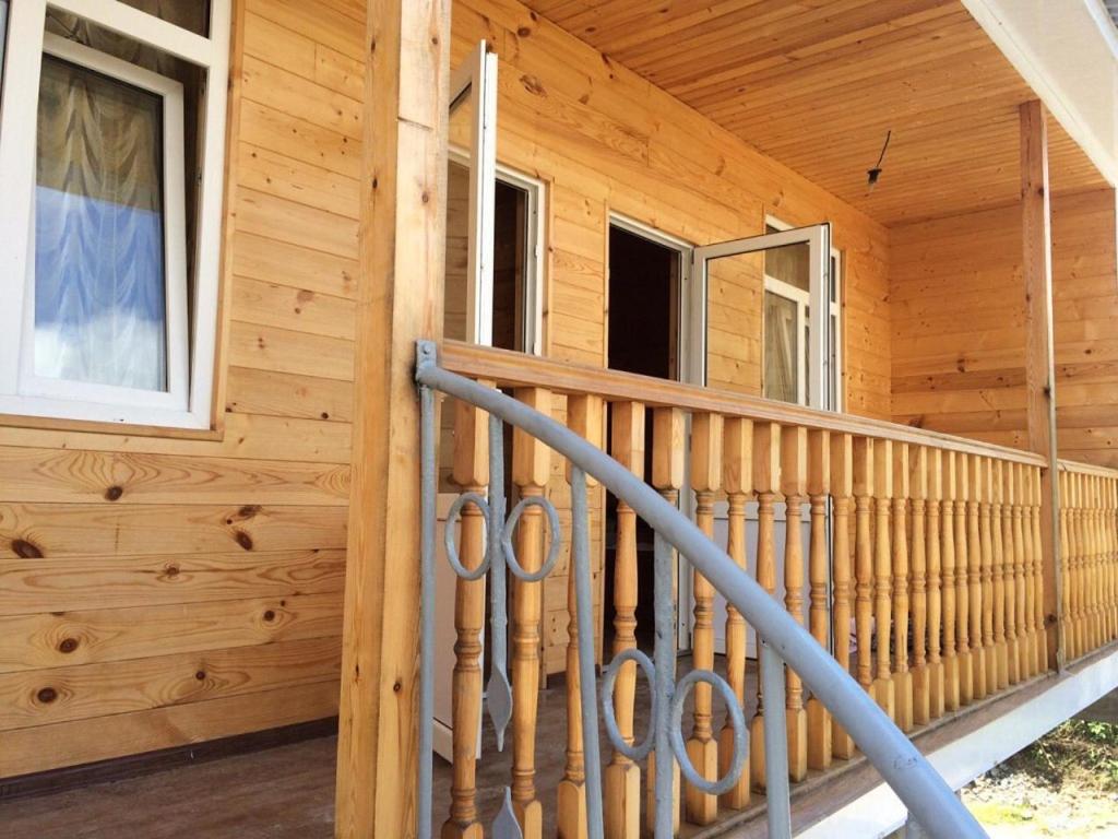 a front porch of a wooden house with a railing at At Alla's in Novy Afon