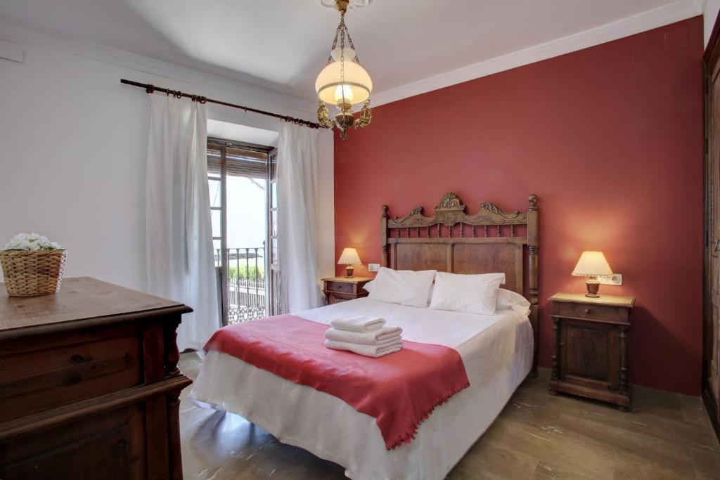 a bedroom with a bed with a red wall at Casa Rondeña in Ronda