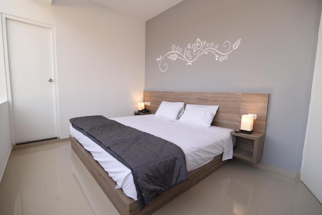 a bedroom with a large bed with white sheets at Hotel Escala in Chiclayo