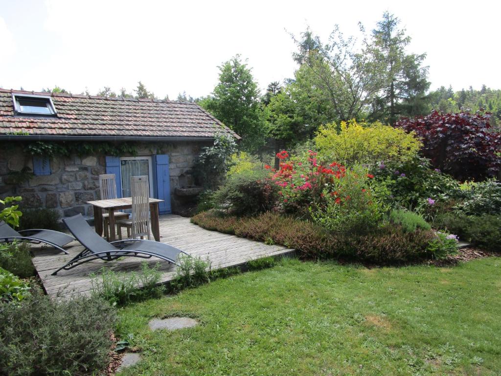 um pátio com uma mesa e cadeiras num jardim em Gîte d'Odile em Le Chambon-sur-Lignon