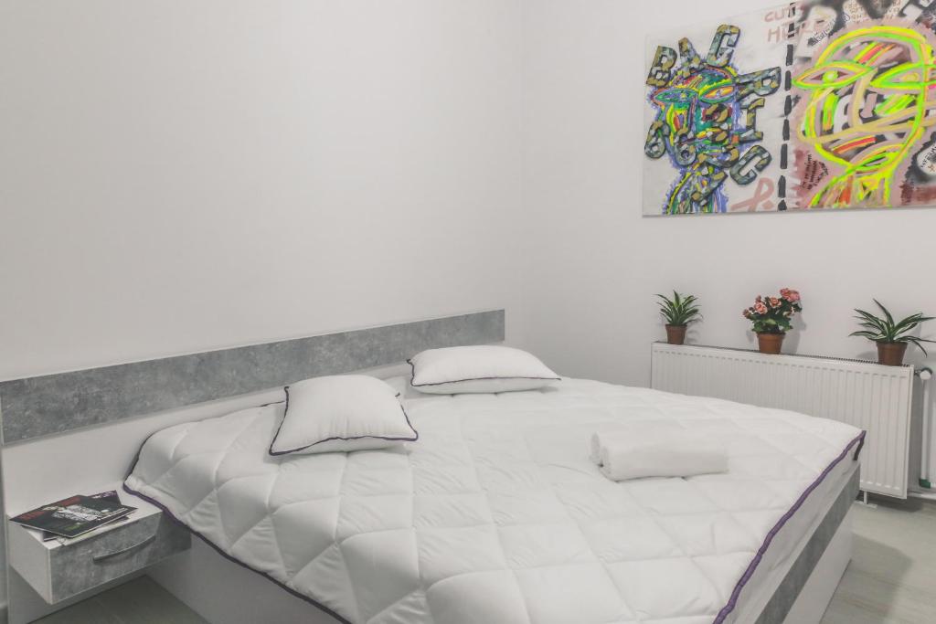 a white bedroom with a large white bed with pillows at Victoria Duplex Apartament in Bucharest