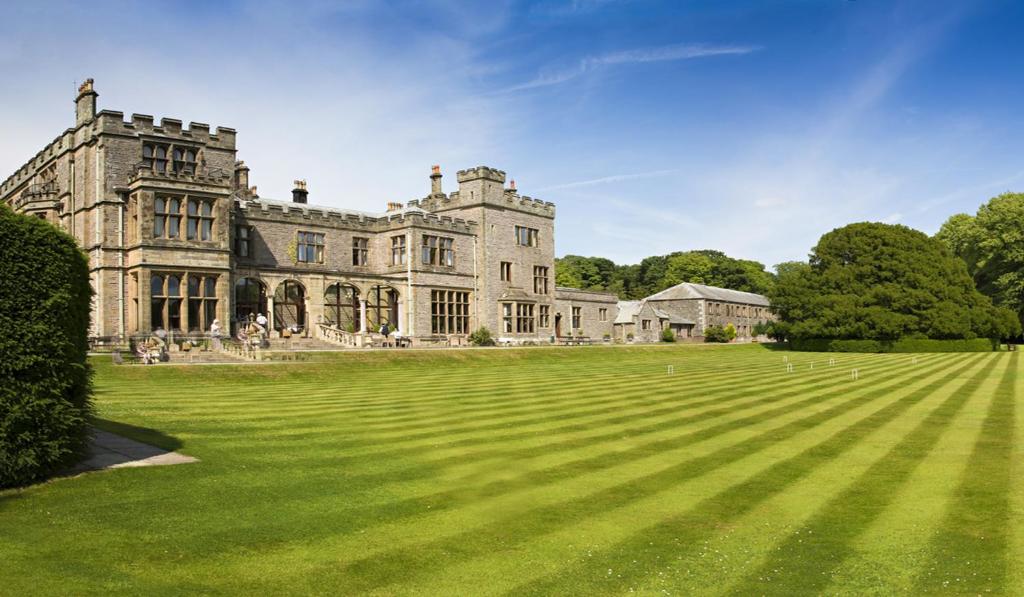 an old castle with a large grass field at Armathwaite Hall Hotel & Spa in Bassenthwaite