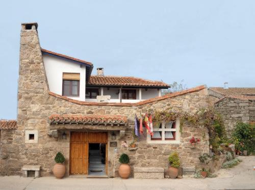 una casa de piedra con un edificio con una puerta en Posada Real La Mula de los Arribes en Villardiegua de la Ribera
