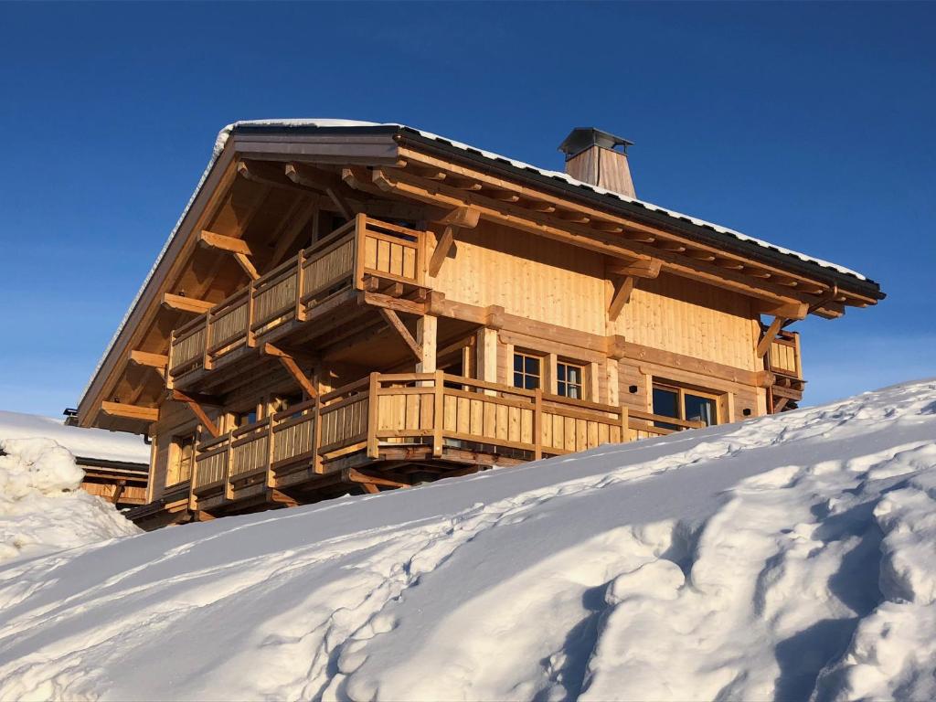 una baita di tronchi situata in cima a un pendio innevato di Chalet Nanook a Notre-Dame-de-Bellecombe