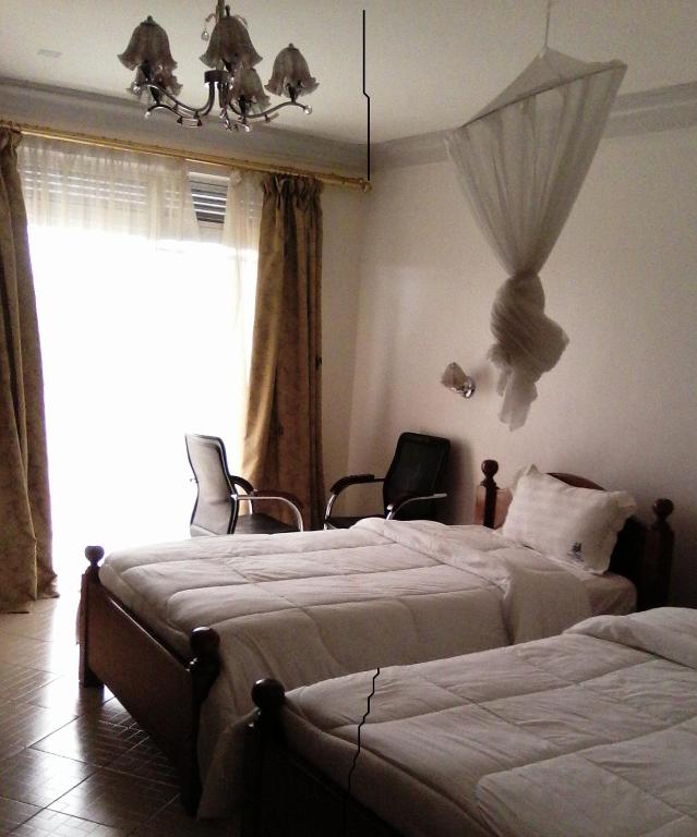 a bedroom with two beds and a window at Western Meridian Hotel Ltd Bushenyi in Bushenyi