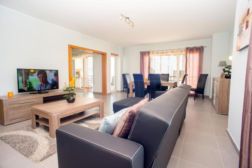 een woonkamer met een bank, een tv en een tafel bij Pegada By Algartur in Tavira