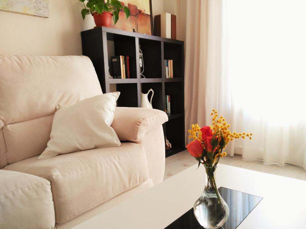 una sala de estar con sofá y un jarrón de flores sobre una mesa en Apartamento en centro histórico con garaje propio, en Jerez de la Frontera