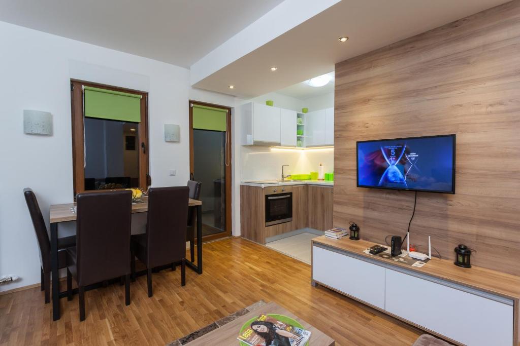 un soggiorno con un tavolo e una televisione su una parete di Astra Apartment a Zlatibor