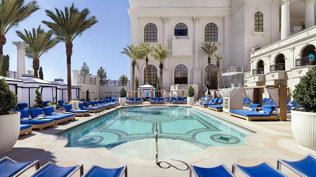 a pool in the lobby of a hotel with blue chairs and palm trees at Caesars Palace Hotel & Casino in Las Vegas