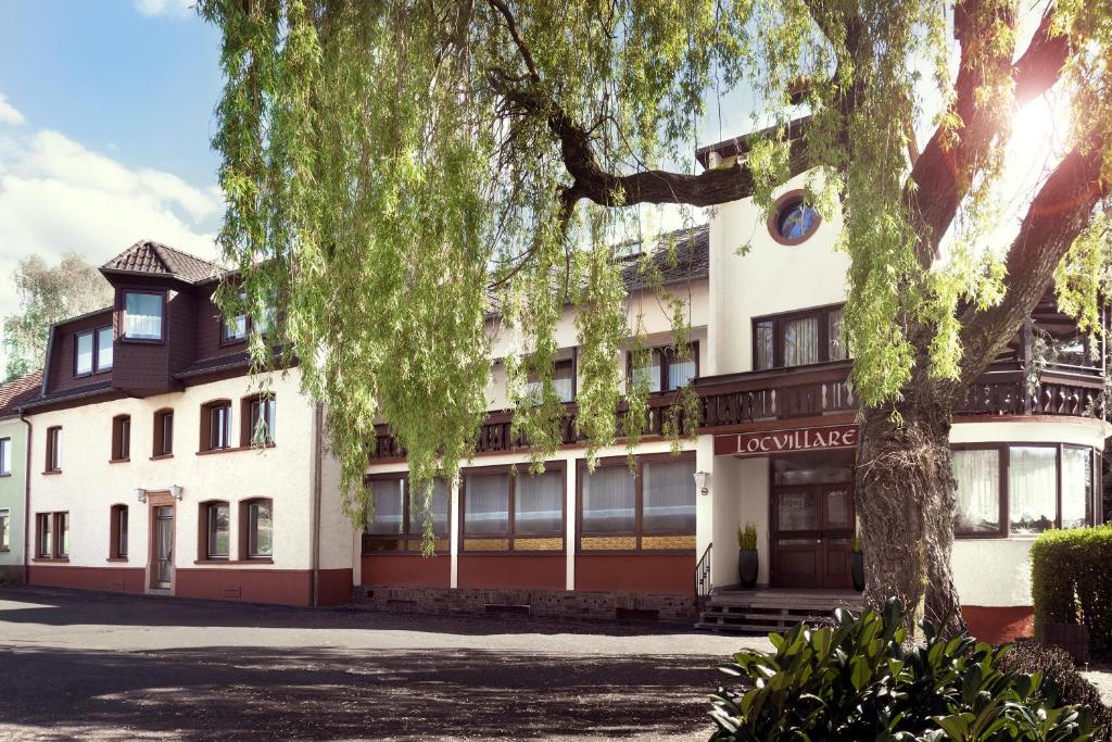 um edifício com uma árvore em frente em Locvillare em Wadern