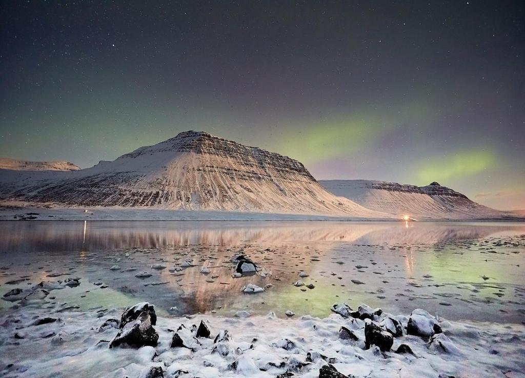 an image of a mountain with the aurora in the sky at Sudavik guesthouse in Súðavík