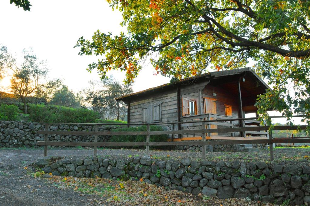 a small wooden cabin with a stone wall at Agriturismo Kikajon in Linguaglossa