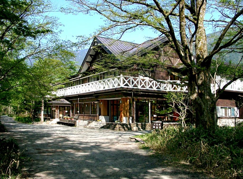 duży dom z drzewem przed nim w obiekcie Kamikochi Nishi-itoya Mountain lodge w mieście Matsumoto