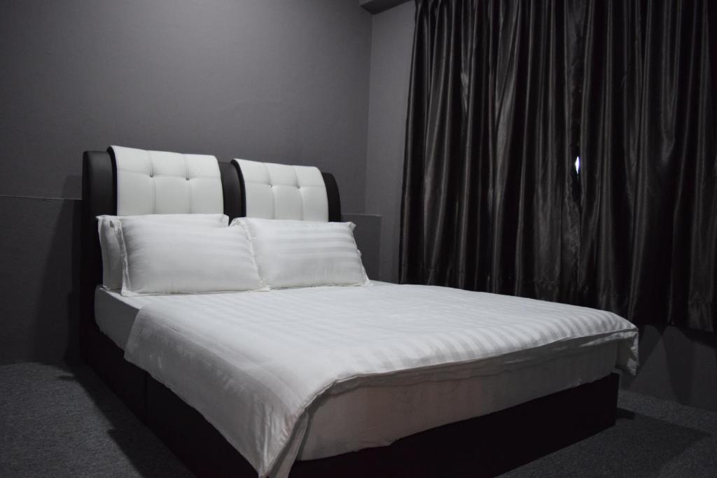 uma cama com lençóis brancos e almofadas ao lado de uma janela em Times Traveller Lodge 2 em Kota Belud