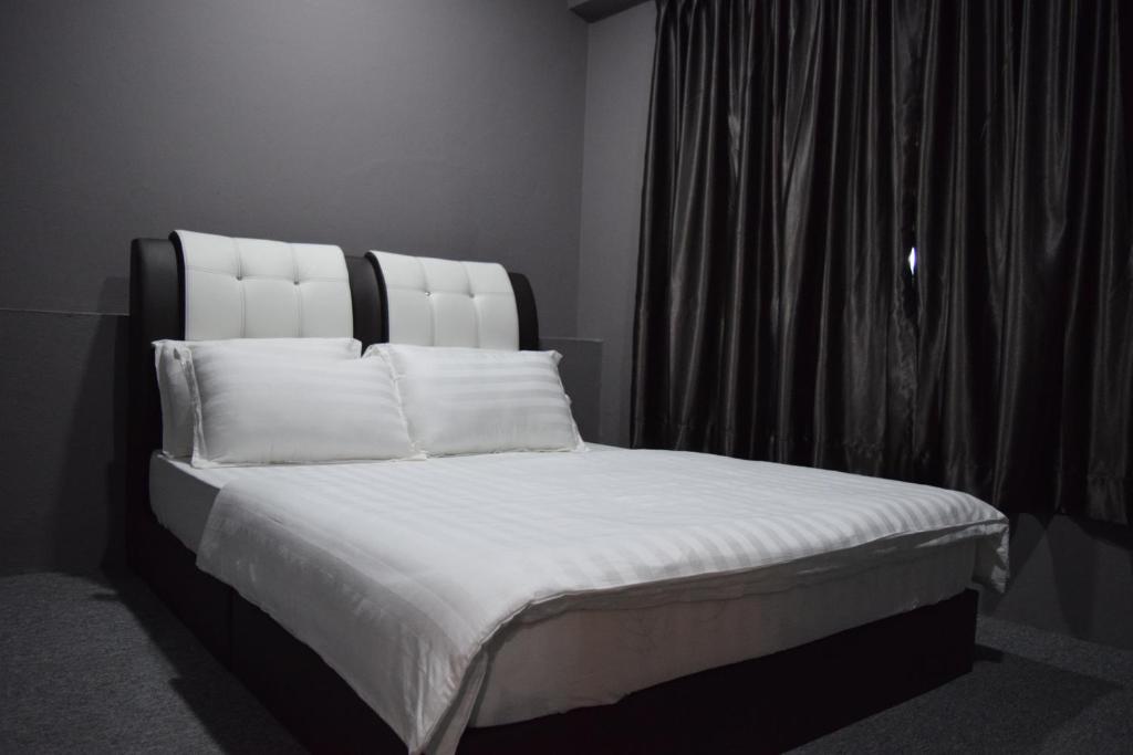 a bed with white sheets and pillows next to a window at Times Traveller Lodge 2 in Kota Belud