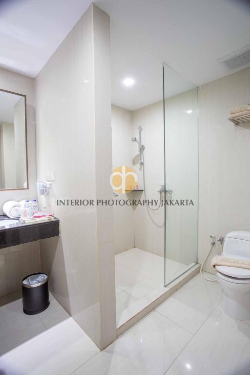 a bathroom with a glass shower and a toilet at Orchardz Hotel Bandara in Tangerang
