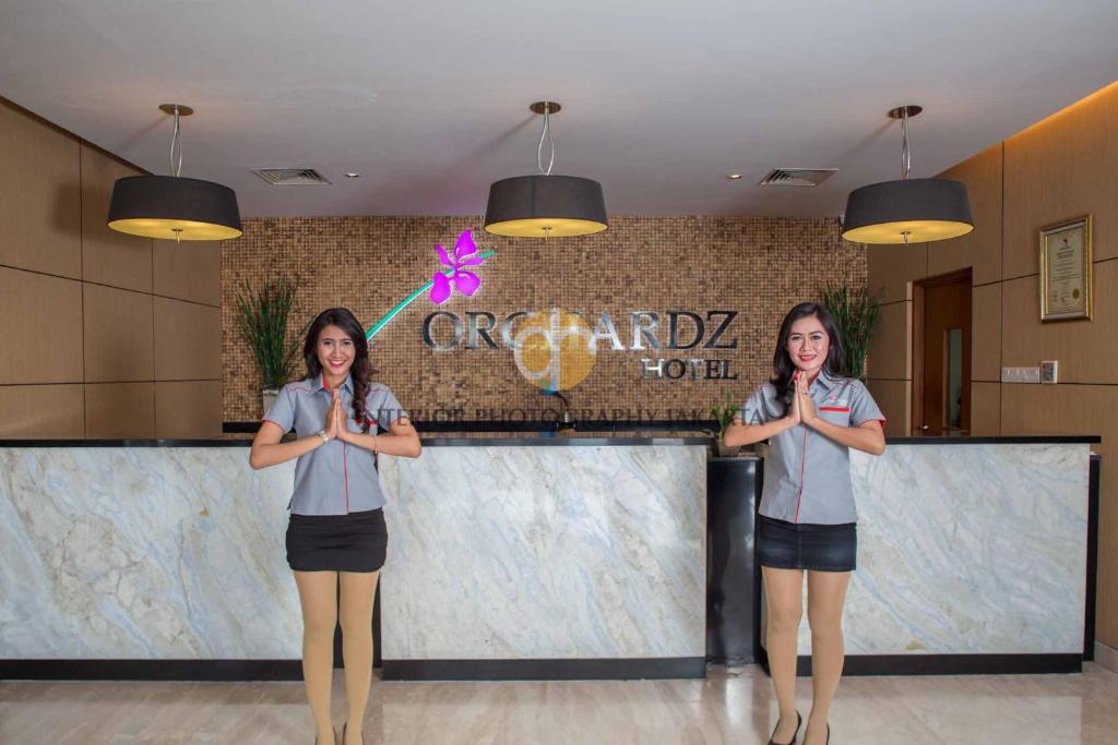 two women standing in front of a counter with their hands at Orchardz Hotel Bandara in Tangerang