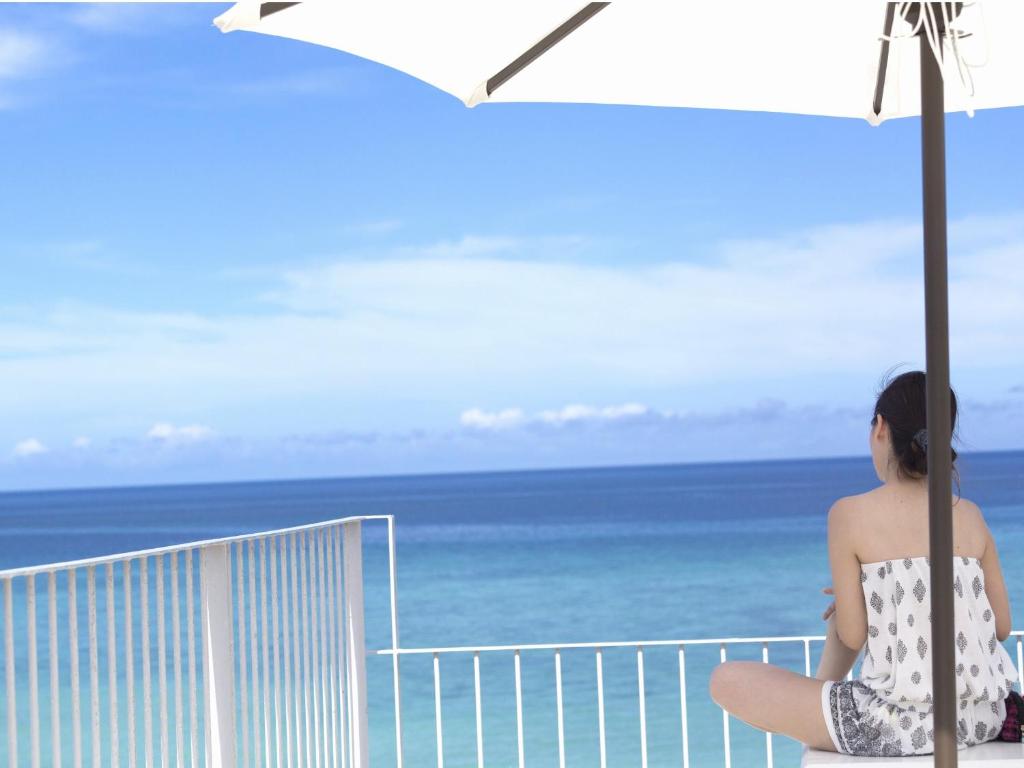 石垣島にあるSeven Colors 石垣島　（セブンカラーズ石垣島）の浜辺の傘の下に座る女