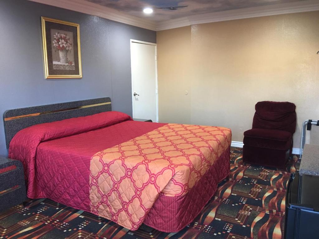 a bedroom with a red bed and a chair at Budget Inn LAX-Lawndale in Lawndale