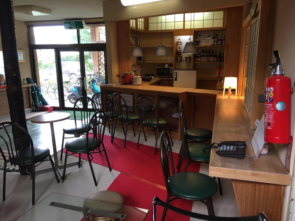 a restaurant with a bar with green chairs and a red rug at Towadako Hostel in Towada