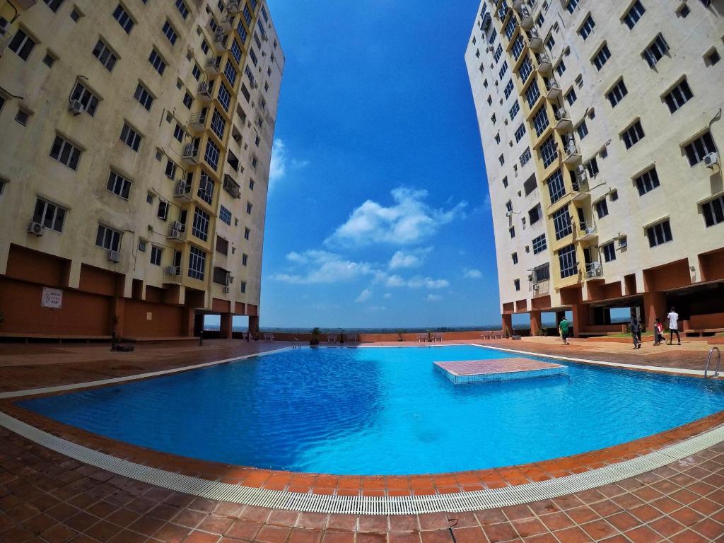 une grande piscine bleue entre deux grands bâtiments dans l'établissement Sultan Bridge Place, à Kota Bharu
