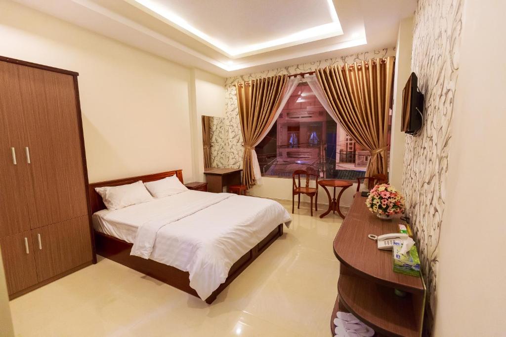 a bedroom with a bed and a desk and a window at VẠN LỘC HOTEL in Can Tho