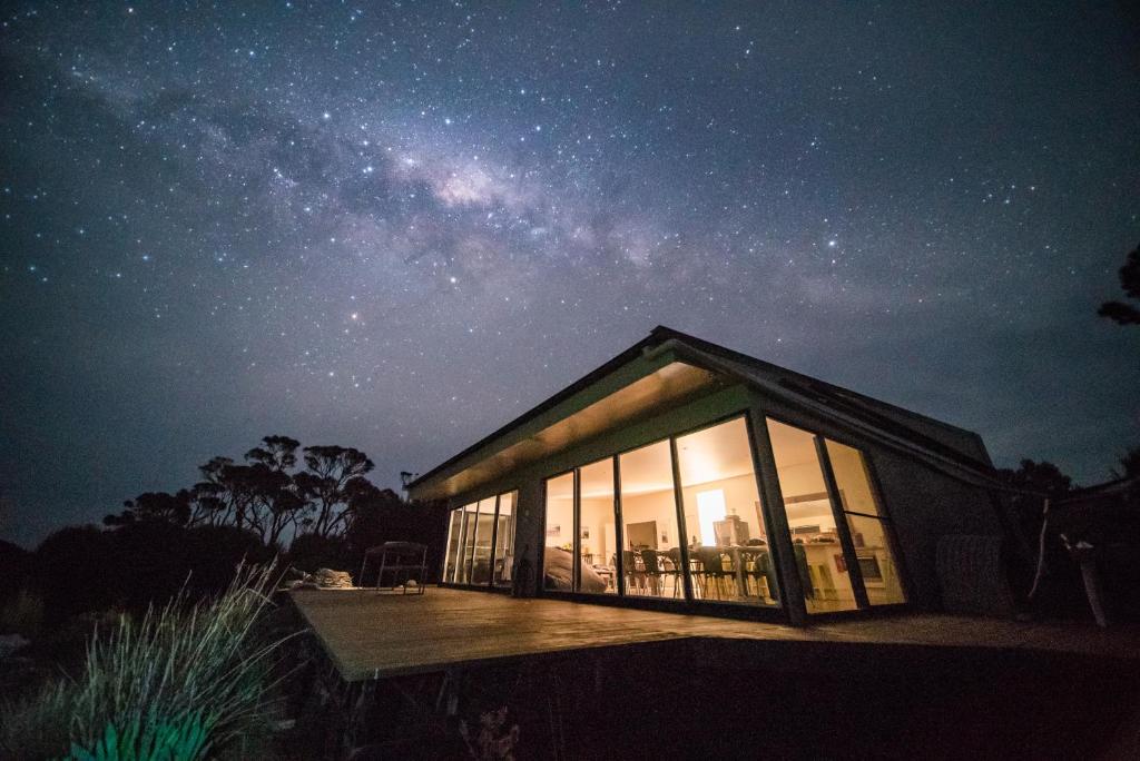 una pequeña casa con un cielo estrellado por la noche en Sawyers Bay Shacks, en Emita