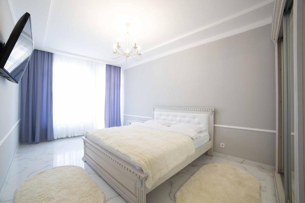 リヴィウにあるLEOGRAND Apartments on Kulisha 36の白いベッドルーム(ベッド1台、シャンデリア付)