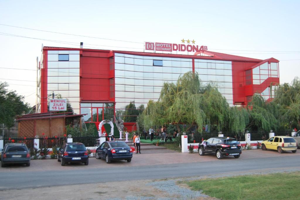 un edificio rojo y blanco con coches estacionados en un estacionamiento en Motel Didona B, en Galaţi