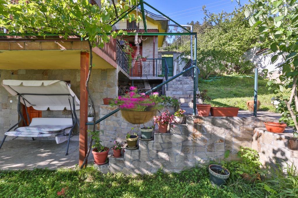 a house with a balcony and a chair and potted plants at Guest House Villa Teres in Shipka