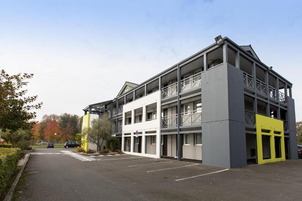 um edifício com um parque de estacionamento em frente em B&B HOTEL Rennes Nord St Grégoire em Saint-Grégoire