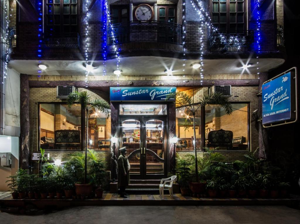 um homem parado em frente a uma loja à noite em Hotel Sunstar Grand em Nova Deli
