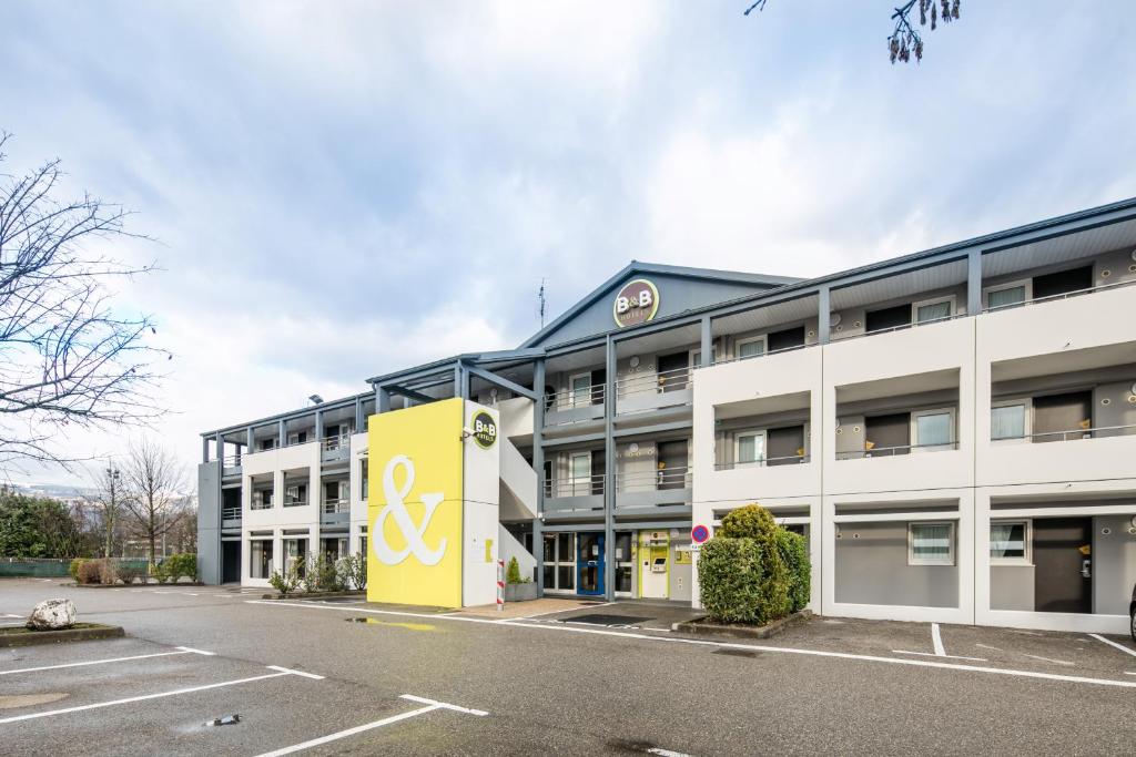 un edificio de oficinas con un edificio amarillo y blanco en B&B HOTEL Grenoble Université en Gières