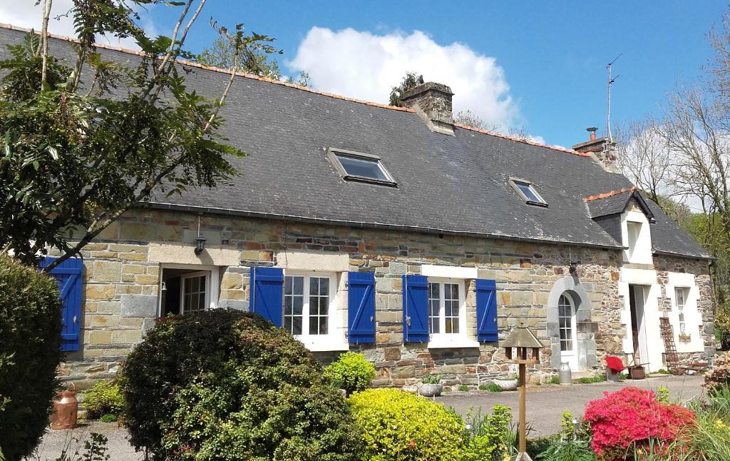 ein altes Steinhaus mit blauen Fensterläden in der Unterkunft Couloumine breizh in Saint-Aignan