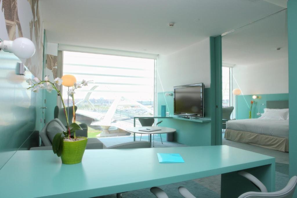 a blue room with a table and a bed at Hotel Hiberus in Zaragoza