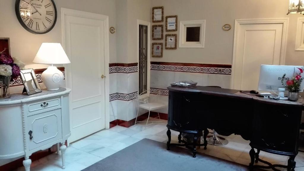 een kamer met een bureau met een computer en een klok bij Le Petit Paris in Sevilla