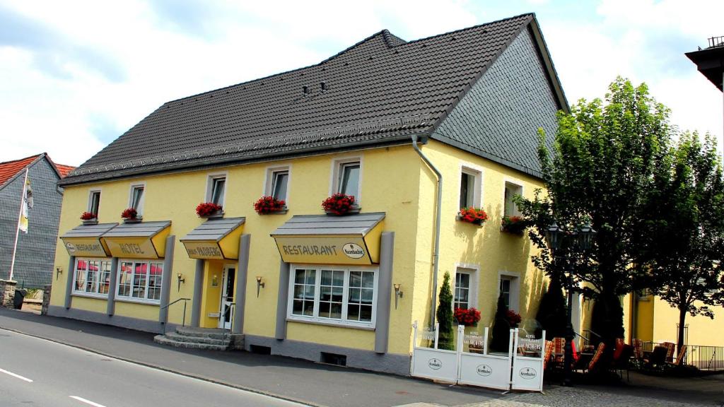 a yellow building with a black roof on a street at Haus Padberg in Balve