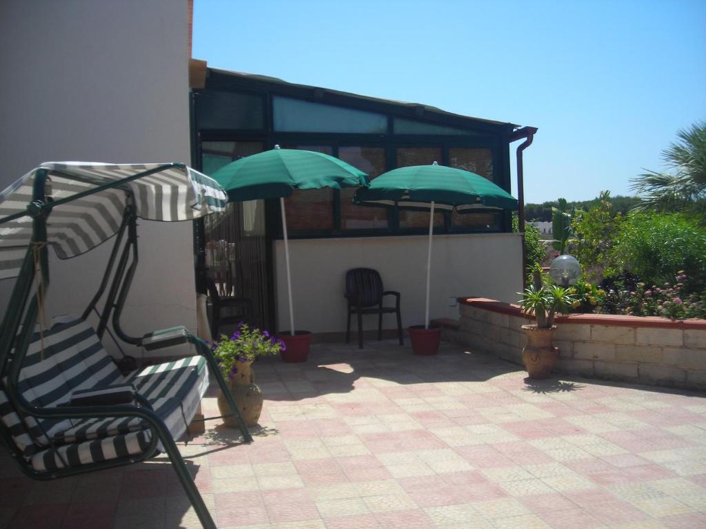 un patio con una sedia e 2 ombrelloni di Favignana Like Home a Favignana